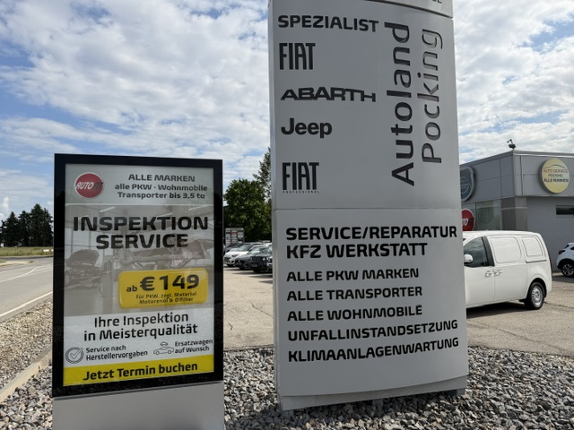 Das Außenschild des Autohauses mit einem Werbebanner für einen Inspektionservice für 149 Euro